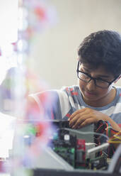 Fokussierter Junge, der einen Computer im Klassenzimmer zusammenbaut - CAIF26582