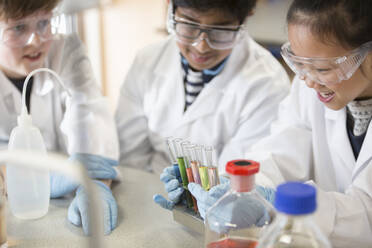 Students examining liquids in test tube rack, conducting scientific experiment in laboratory classroom - CAIF26583