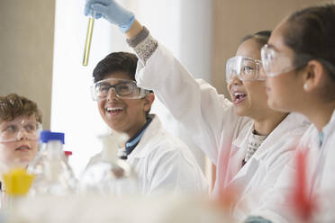 Students examining liquid in test tube, conducting scientific experiment in laboratory classroom - CAIF26589