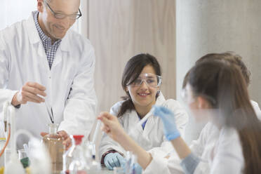 Male teacher and students conducting scientific experiment in laboratory classroom - CAIF26590