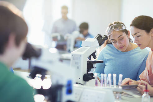 Lehrerin und Schülerin bei der Durchführung eines wissenschaftlichen Experiments am Mikroskop in einem Labor-Klassenzimmer - CAIF26602