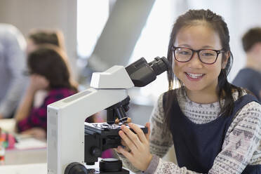 Porträt einer lächelnden, selbstbewussten Studentin, die ein Mikroskop benutzt und ein wissenschaftliches Experiment in einem Laboratorium durchführt - CAIF26610