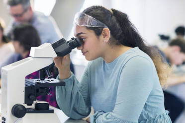 Studentin mit Mikroskop, die ein wissenschaftliches Experiment im Laboratorium durchführt - CAIF26613