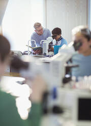 Ein männlicher Lehrer und ein Schüler benutzen ein Mikroskop und führen ein wissenschaftliches Experiment in einem Laboratorium durch - CAIF26616