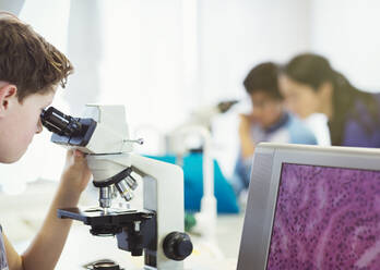 Junge Student, der ein Mikroskop benutzt und ein wissenschaftliches Experiment in einem Laboratorium durchführt - CAIF26624