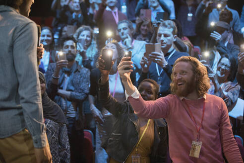 Lächelndes Publikum mit Smartphone-Taschenlampen für den Sprecher - CAIF26661