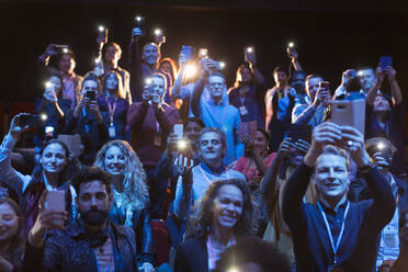 Gespanntes Publikum mit Smartphone-Taschenlampen im dunklen Hörsaal - CAIF26670