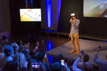 Publikum beobachtet männlichen Redner mit Virtual-Reality-Simulatorbrille auf der Bühne - CAIF26718
