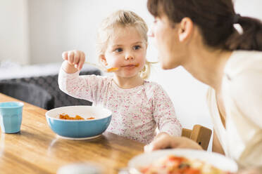 Daughter feeding mother with spoon at home - SDAHF00764
