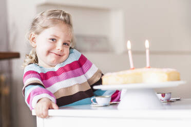 Lächelndes Mädchen sitzt am Tisch mit Geburtstagskuchen - SDAHF00769