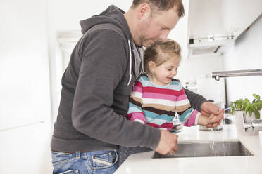 Vater und Tochter waschen sich in der Küche die Hände - SDAHF00773