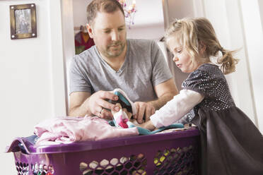 Girl helping father with laundry at basket - SDAHF00778