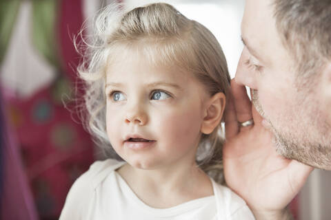 Father whispering in dauthter's ear stock photo