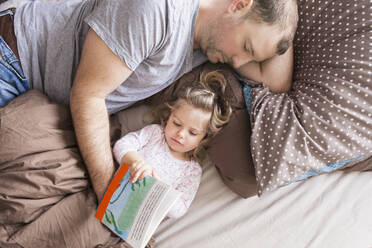 Father and daughter reading a book in bed - SDAHF00786
