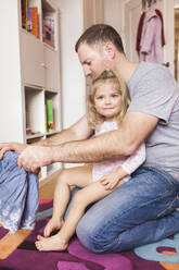 Father dressing his daughter at home - SDAHF00790