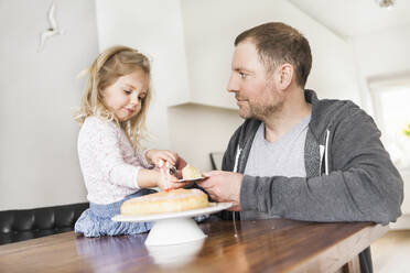 Vater und Tochter spielen mit Puppengeschirr und einem Stück Kuchen auf einem Teller - SDAHF00791