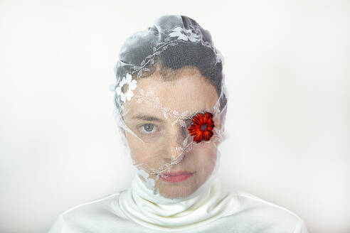 Porträt einer jungen Frau mit weißem Schleier und roter Blume über einem Auge - PSTF00729