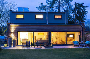 Beleuchtetes Haus mit Möbeln im Hinterhof in der Abenddämmerung - BFRF02240