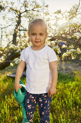 Porträt eines niedlichen blonden Mädchens, das eine Gießkanne hält und am Wochenende im Garten steht - ZEDF03356