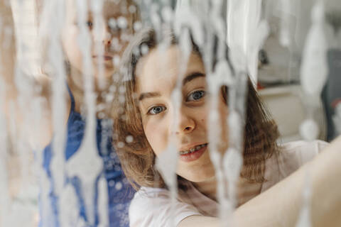 Porträt eines Teenagers, der durch eine nasse Fensterscheibe schaut, lizenzfreies Stockfoto