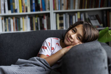 Porträt eines lächelnden Jungen, der sich an ein bequemes Sofa im Wohnzimmer anlehnt - VABF02882