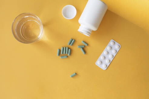 Studio shot of glass of water, pills blister pack, pill bottle and nutritional supplement capsules - MOMF00856