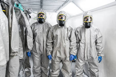 Portrait of sanitation workers standing in protective coverall suits during pandemic - JCMF00663