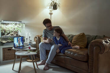 Arzt führt Videogespräch mit krankem Mädchen und ihrem Vater über Laptop zu Hause - ERRF03645