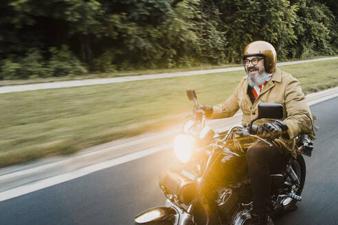 Porträt eines glücklichen Mannes beim Motorradfahren - HWHF00020