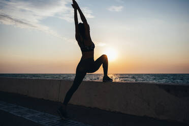 Silhouette woman practicing yoga at promenade during sunrise - OYF00134
