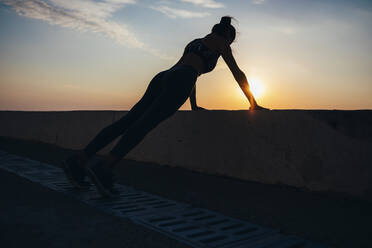 Silhouette Frau macht Liegestütze an der Promenade bei Sonnenaufgang - OYF00136