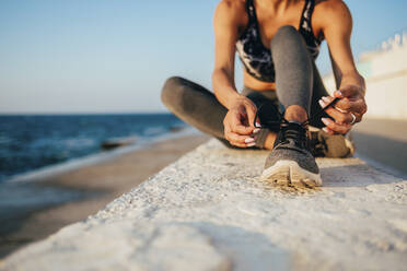 Low section of young woman tying shoelace on promenade - OYF00141