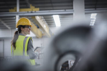 Selbstbewusste Arbeiterin mit digitalem Tablet in einem Stahlwerk - CAIF26752
