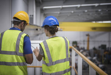 Aufsichtspersonen besprechen Papierkram auf einer Plattform in einer Fabrik - CAIF26764