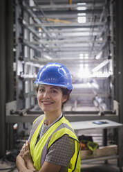 Porträt einer lächelnden, selbstbewussten Arbeiterin in einer Stahlfabrik - CAIF26768