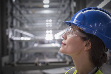 Profile pensive female worker looking up in factory - CAIF26772