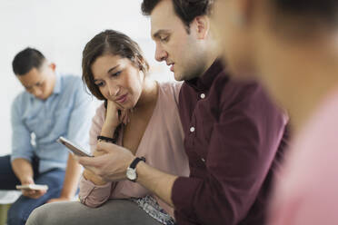 Businessman showing digital tablet to businesswoman in meeting - CAIF26833