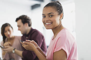 Portrait smiling, confident businesswoman texting with smart phone in office - CAIF26837