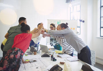 Enthusiastic architects high-fiving in conference room meeting - CAIF26839