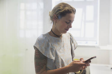 Woman with tattoos texting with smart phone - CAIF26841