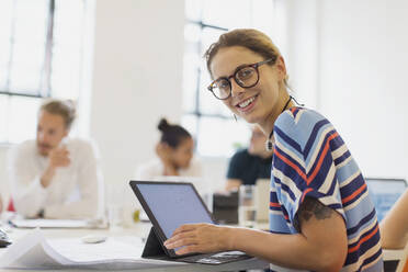 Porträt einer lächelnden, selbstbewussten Architektin, die in einem Konferenzraum an einem Laptop arbeitet - CAIF26843