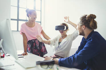 Computer programmers testing virtual reality simulator glasses at computer in office - CAIF26858