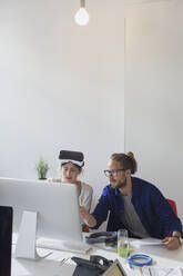 Computerprogrammierer beim Programmieren einer Virtual-Reality-Simulator-Brille am Computer im Büro - CAIF26903