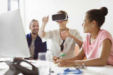 Computer programmers testing virtual reality simulator glasses at computer in office - CAIF26911