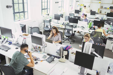 Geschäftsleute arbeiten an Schreibtischen in einem Großraumbüro - CAIF26925