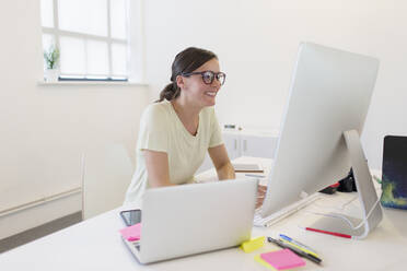 Lächelnde Geschäftsfrau bei der Arbeit am Computer im Büro - CAIF26942