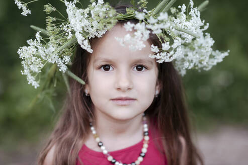 Portrait of cute girl wearing white flowers at park - EYAF01058