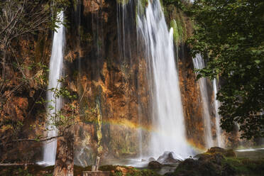 Kroatien, Kleiner Regenbogen über plätscherndem Wasserfall im Nationalpark Plitvicer Seen - ABOF00515