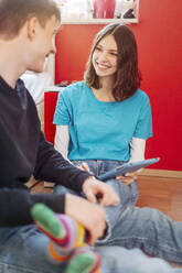 Porträt eines lächelnden Teenagers mit digitalem Tablet, der seinen Freund anschaut - STDF00214