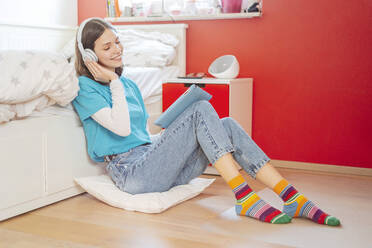 Portrait of smiling teenage girl with eyes closed listening music with headphones and digital tablet - STDF00216